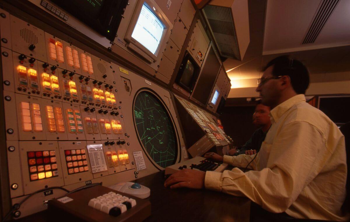 Two air traffic controllers look at a radar screen in an area control centre. 